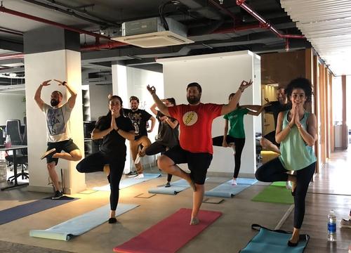 Group holding tree pose in an office space