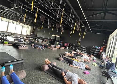 Class resting in savasana in a large studio